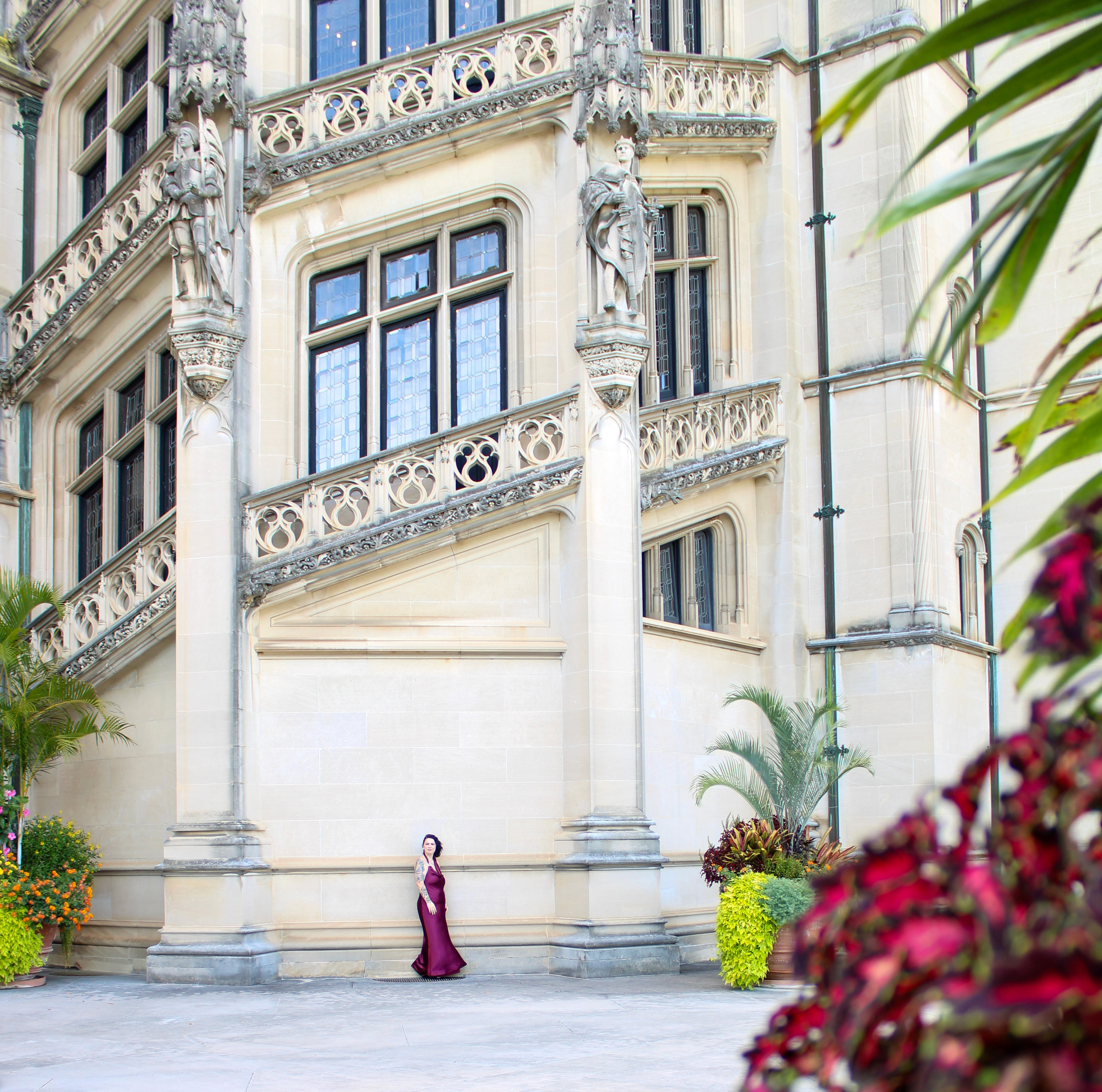 Woman in burgundy dress against an ornate building facade