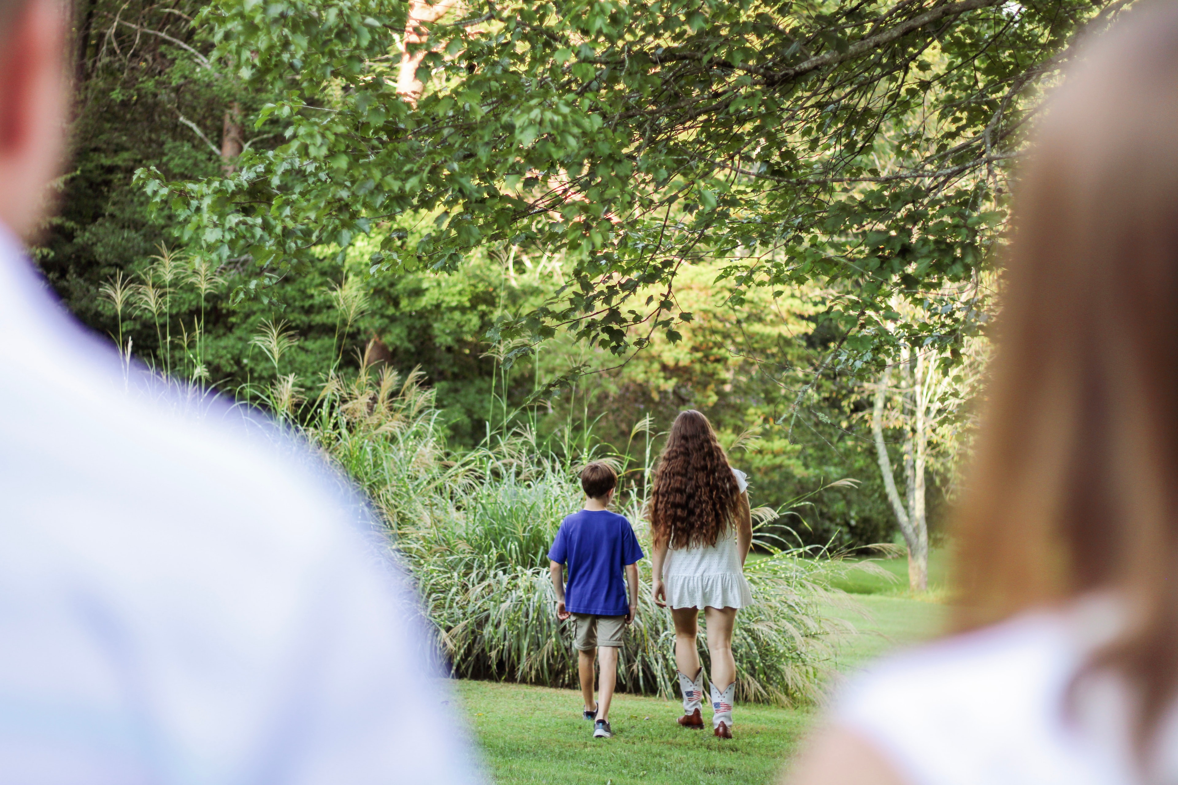 Children jogging through a tree-lined garden path