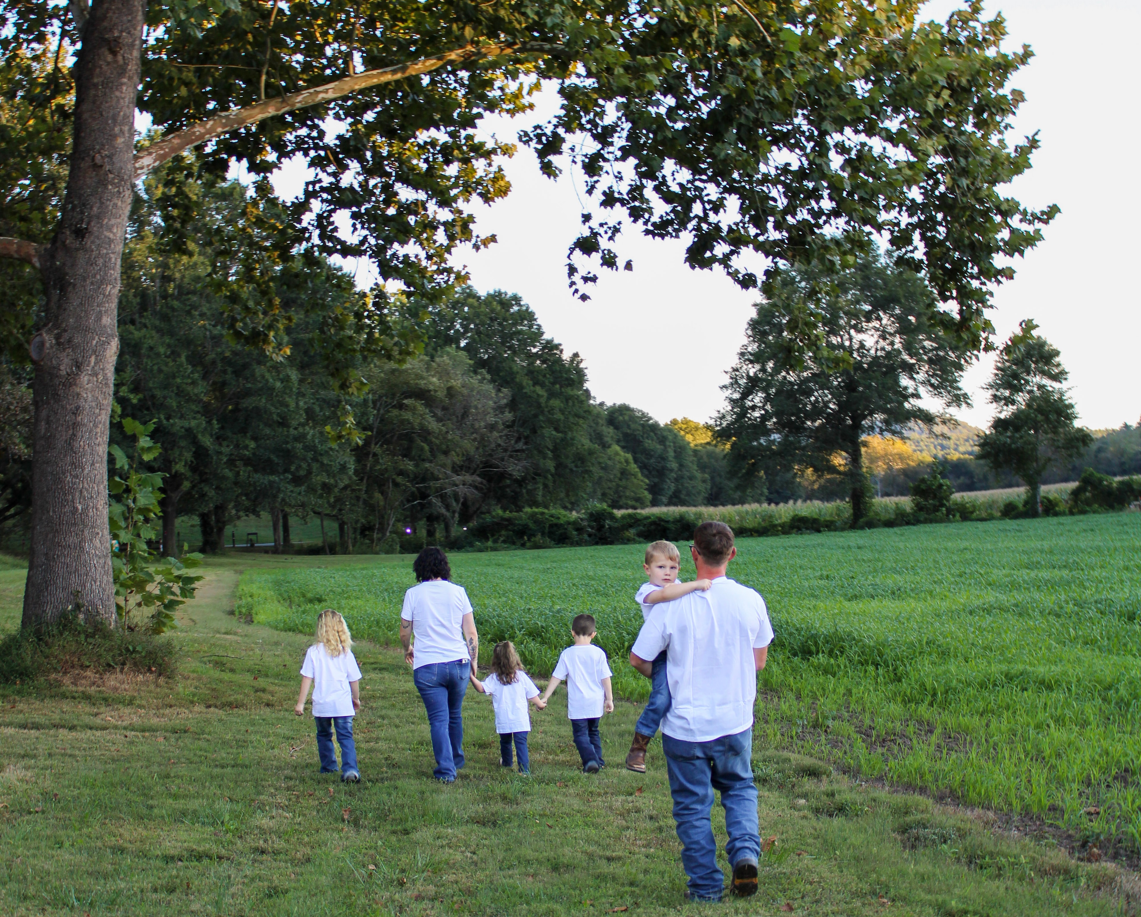 Family walking through a grassy field at golden hour